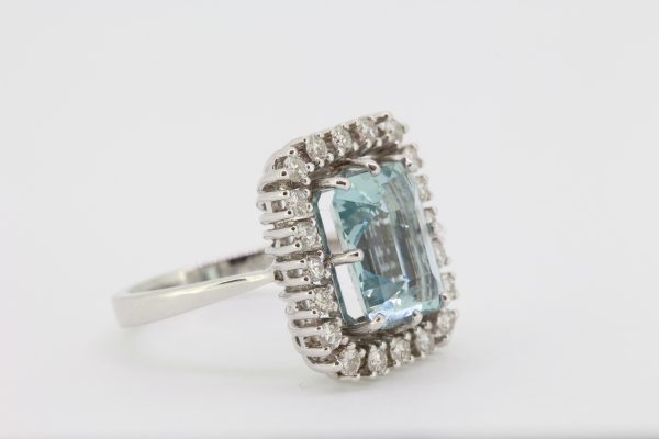 Emerald Cut Aquamarine and Diamond Cluster Ring; central 4.64ct emerald-cut aquamarine within a 0.95ct diamond surround, in 18ct white gold