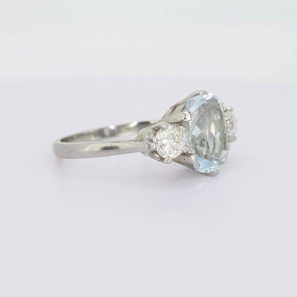 Aquamarine and Diamond Three Stone Ring in Platinum; central 2.80ct oval cushion-shaped aquamarine flanked by 0.55cts brilliant cut diamonds