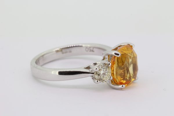 Orange Sapphire and Diamond Three Stone Ring; central 4.30ct orange sapphire set between two round brilliant-cut diamonds, 0.72cts, in 18ct white gold