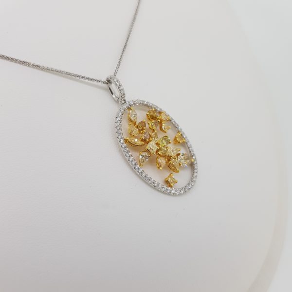 Fancy Yellow and White Diamond Pendant; featuring fancy yellow diamonds in a floral open design surrounded by an oval halo of white diamonds