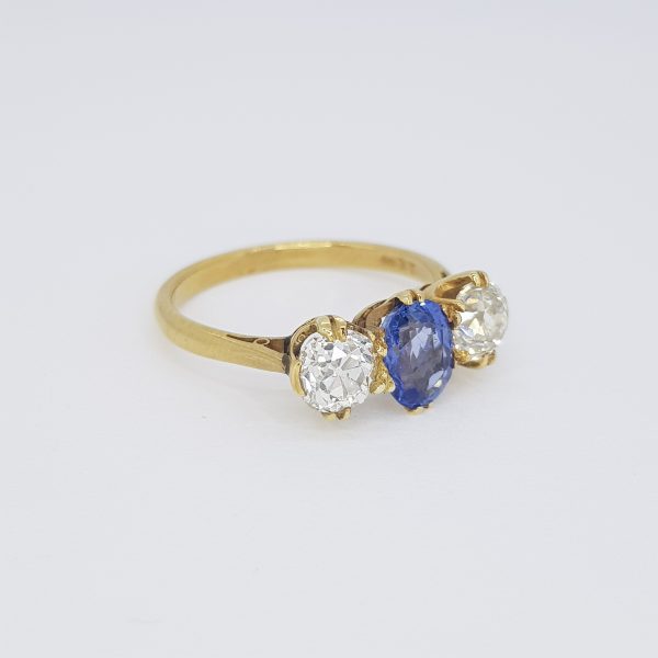 Natural Sapphire and Old Cut Diamond Three Stone Ring; 1.10ct oval faceted natural sapphire flanked by 1.10cts old cut diamonds, in 18ct yellow gold