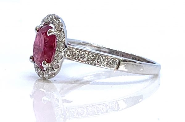 Ruby and Diamond Halo Cluster Engagement Ring; 1.71ct oval ruby with no indication of heat treatment with diamond halo and diamond shoulders, 18ct white gold