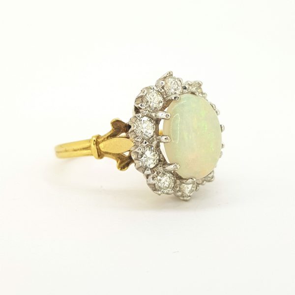 Opal and Diamond Cluster Ring in 18ct Yellow Gold; central oval cabochon cut opal surrounded by sparkling diamonds, claw set in white gold, mounted to yellow gold band