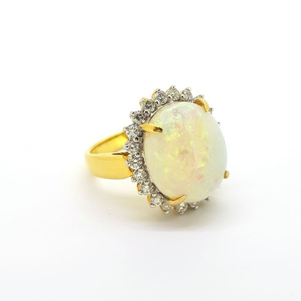 Opal and Diamond Cluster Ring; featuring a large oval cabochon-cut opal of 7.21 carats surrounded by 0.84cts diamonds, in 18ct yellow gold