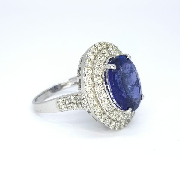 Tanzanite and Diamond Oval Cluster Dress Ring; central 9.89 carat oval tanzanite with a double halo of diamonds and diamond-set shoulders, in 18ct white gold