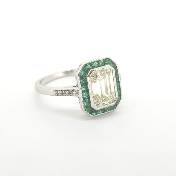 Contemporary Diamond and Emerald Cluster Ring; 1.61ct emerald-cut diamond within calibre-cut emerald surround accented with diamond-set shoulders, in 18ct white gold