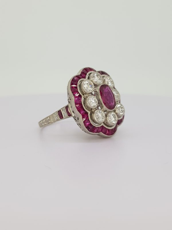 Art Deco Style Ruby and Diamond Floral Cluster Ring; central oval faceted ruby surrounded by eight brilliant-cut diamonds, all within an outer border of calibre-cut rubies, in platinum, Rubies 1.62 carats, Diamonds 1.25 carats