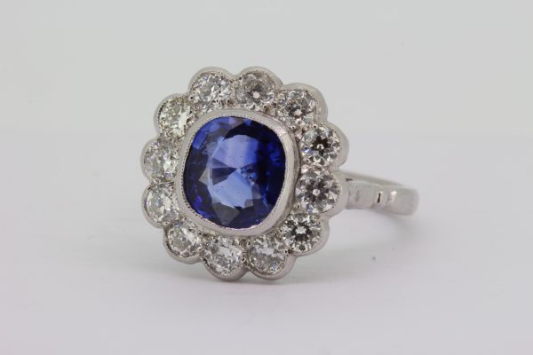 Cushion Cut Sapphire and Old Cut Diamond Floral Cluster Ring; 2.25ct cushion-cut fine colour sapphire, collet set and surrounded with 1.05cts old cut diamonds, in platinum