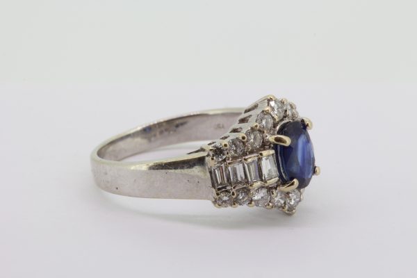 Sapphire and Diamond Cluster Dress Ring; central oval sapphire flanked either side by a row of baguette-cut diamonds, with a brilliant-cut diamond border to the top and bottom, in 18ct white gold
