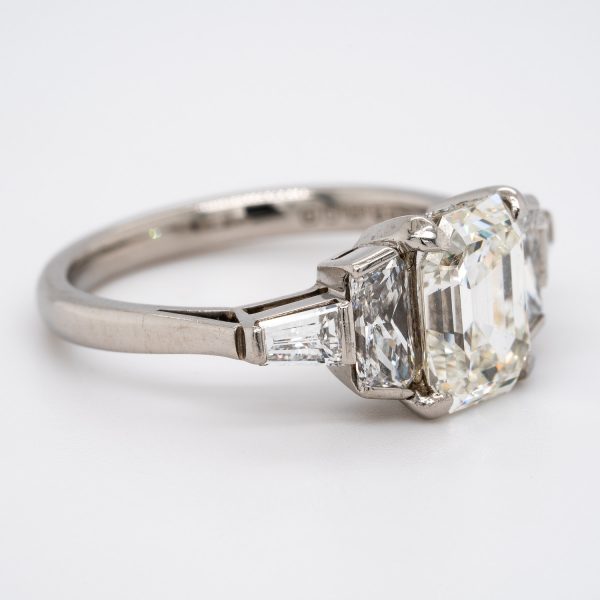 Vintage Diamond Three Stone Ring in Platinum; certified 1.71ct emerald-cut diamond flanked by scissor-cut diamonds with tapered baguette-cut diamonds to the shoulders