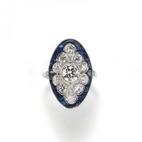 Art Deco Style Sapphire and Old Cut Diamond Cluster Plaque Ring; central old European-cut diamond within a diamond surround and outer calibre sapphire border, in platinum