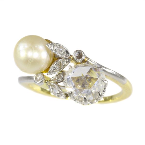 Belle Epoque Rose Cut Diamond and Pearl Two Stone Crossover Ring; set with a saltwater pearl and rose-cut diamond, accented with six smaller rose-cut diamonds, in platinum and 18ct yellow gold, Circa 1910