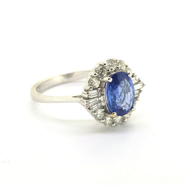 Vintage Sapphire and Diamond Cluster Dress Ring; 1.42ct oval blue sapphire within 0.50ct baguette and brilliant-cut diamond surround in 18ct white gold, Circa 1980