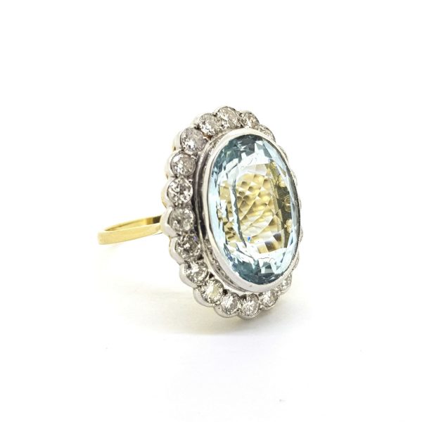 Aquamarine and Diamond Cluster Ring; central 8.10ct oval aquamarine surrounded by 1.20cts diamonds, collet set in 18ct white gold and mounted to an 18ct yellow gold band
