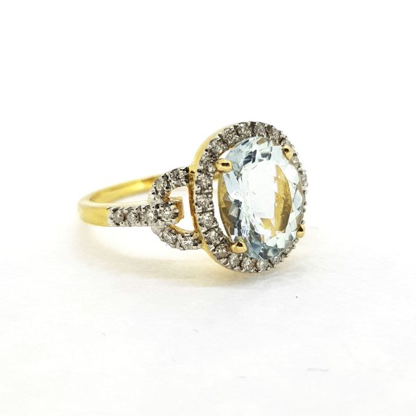 Contemporary Aquamarine and Diamond Cluster Dress Ring; central 2.30ct oval aquamarine within a diamond surround with open semi-circle diamond-set shoulders, in 18ct yellow gold