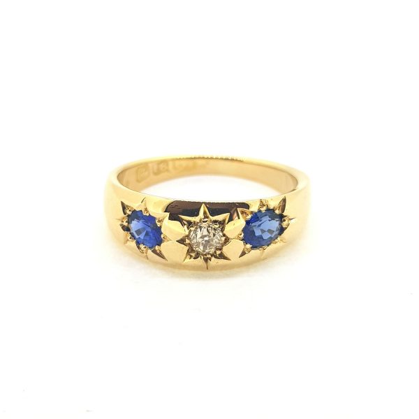 Antique Victorian Sapphire and Diamond Three Stone Ring; central diamond flanked by sapphires, each in star shaped cut down settings in 18ct yellow gold