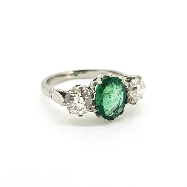 Emerald and Diamond Three Stone Ring in Platinum; central 1.70ct oval emerald flanked by 1.40cts brilliant-cut diamonds