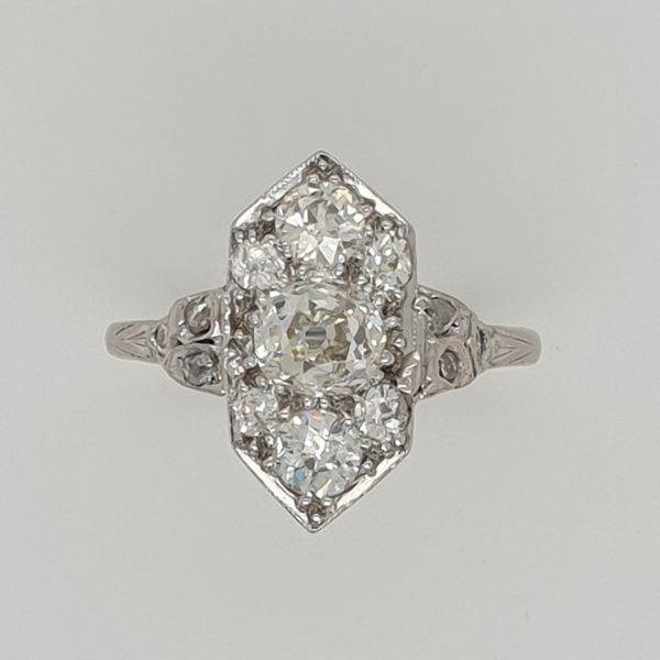 An antique diamond plaque cluster ring with an old mine cut diamond centre surrounded by further diamonds in a long hexagonal cluster and diamond set shoulders
