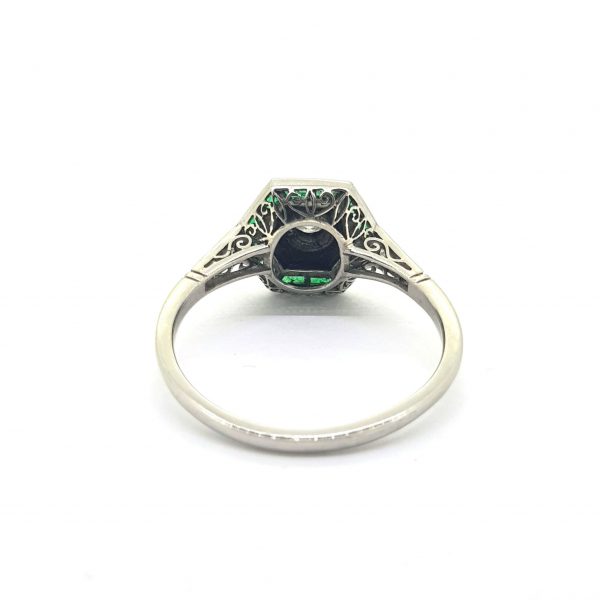 Vintage Art Deco Style Emerald, Diamond and Onyx Ring; 0.20ct J colour VVS1 Old European cut diamond framed with calibre cut emeralds and onyx, decorated with small single cut diamonds to the shoulders, in platinum. Circa 1960s