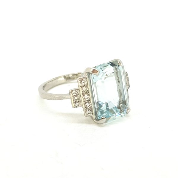 Aquamarine and Diamond Dress Ring in Platinum; central 6ct claw-set emerald-cut aquamarine flanked by 0.25cts diamond-set stepped shoulders