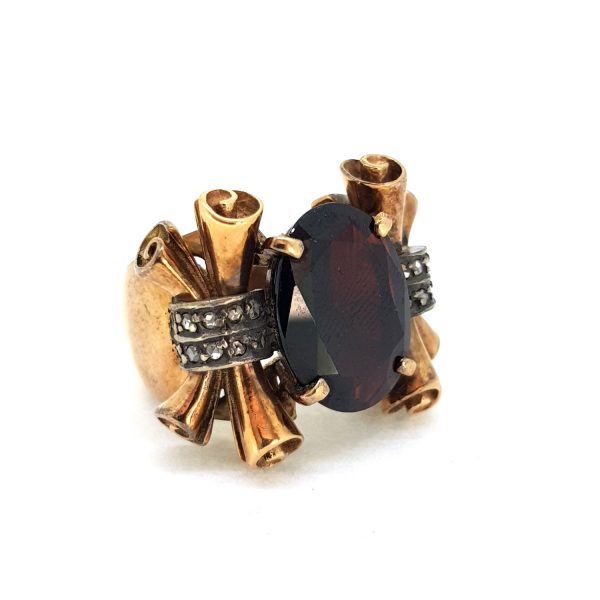 Antique Garnet and Scrolled Gold Dress Ring; central oval garnet nestled within a chunky gold mount accented with decorative scroll shoulders