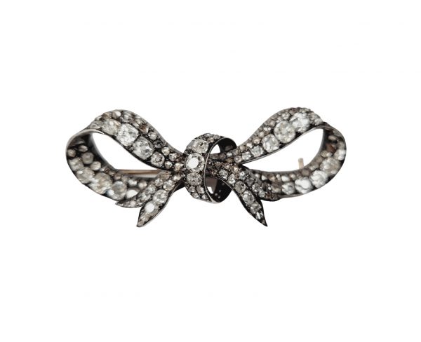 Antique Victorian Old Mine Cut Diamond Bow Brooch; fluid naturalistic lines set with chunky old cut diamonds, in silver and 18ct gold, Engraving to the gold, 19th century
