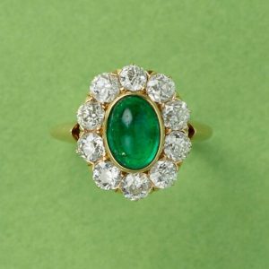 Antique Edwardian Cabochon Emerald and Old Cut Diamond Cluster Ring; 1.54ct oval cabochon cut emerald surrounded by ten old cut diamonds totalling 1.50cts, in 18ct yellow gold. American, Circa 1910