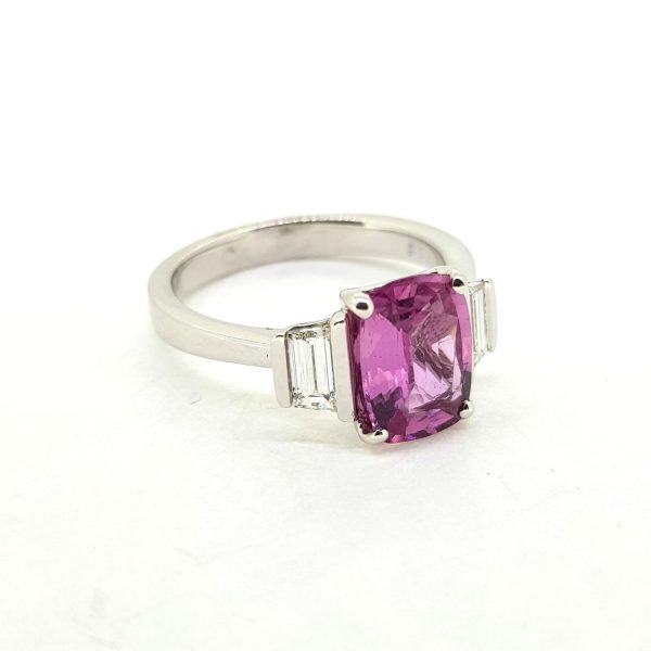 Pink Sapphire and Baguette Diamond Trilogy Ring; central 2.19ct oval pink sapphire flanked by 0.45cts baguette-cut diamonds, in 18ct white gold