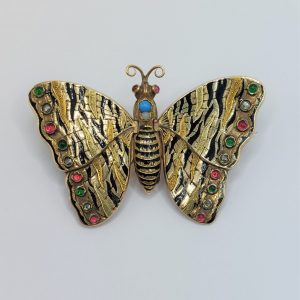 Rare Antique Gold Articulated Butterfly Locket Brooch; green gold butterfly decorated with black enamel tiger stripes and engraving, with cabochon rubies, emeralds and pearls to the wing tips which open to reveal two locket compartments beneath