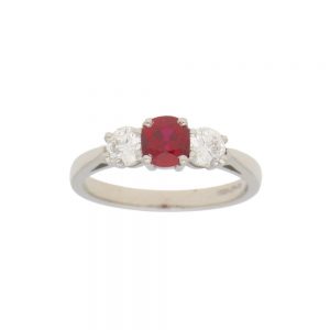 0.98ct Ruby and Diamond Trilogy Engagement Ring; central 0.98ct cushion-cut ruby flanked by 0.62cts brilliant-cut diamonds in 18ct white gold