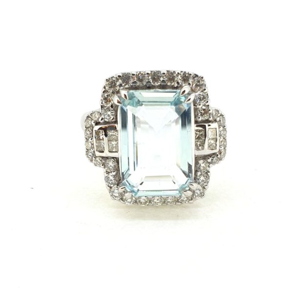 Aquamarine and Diamond Cluster Dress Ring, 3.19ct emerald-shaped aquamarine surrounded by round brilliant-cut diamonds with princess-cut diamonds to the sides in 18ct white gold
