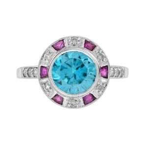 2.75ct Blue Zircon Ring with Ruby and Diamond Halo Cluster, central round-cut blue zircon is surrounded by rubies with a deep pink hue and diamonds with diamond-set shoulders in 14ct white gold