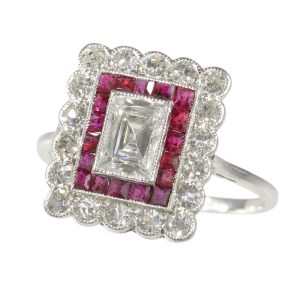 1930s Art Deco engagement ring in platinum, principal emerald cut diamond 0.06 ct surrounded by 18 rubies and 18 brilliant cut diamonds. 