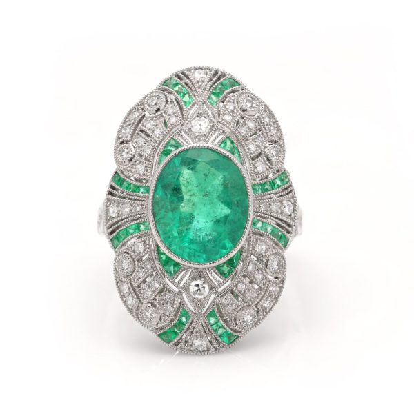 Oval cut emerald ring surround by emeralds and diamonds set in platinum.
