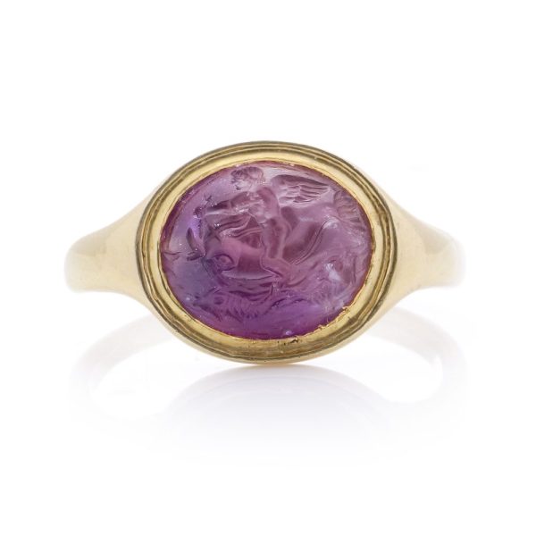 Roman carved intaglio amethyst ring featuring Eros riding a dolphin mounted in gold.