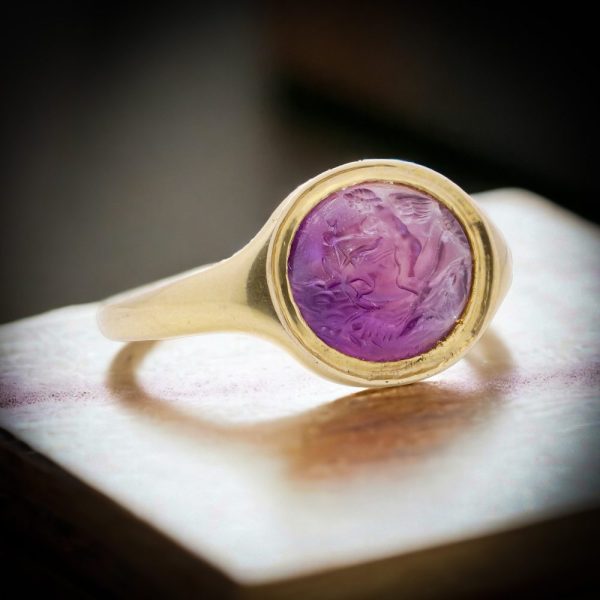 Roman carved intaglio amethyst ring featuring Eros riding a dolphin mounted in gold.