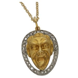 Joker face pendant set in gold with diamonds in platinum.