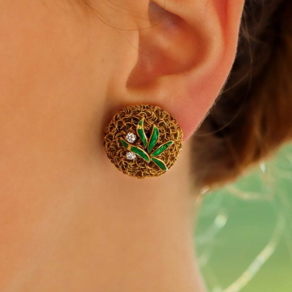 A pair of gold wire work clips earrings set with enamel leaves and diamonds.