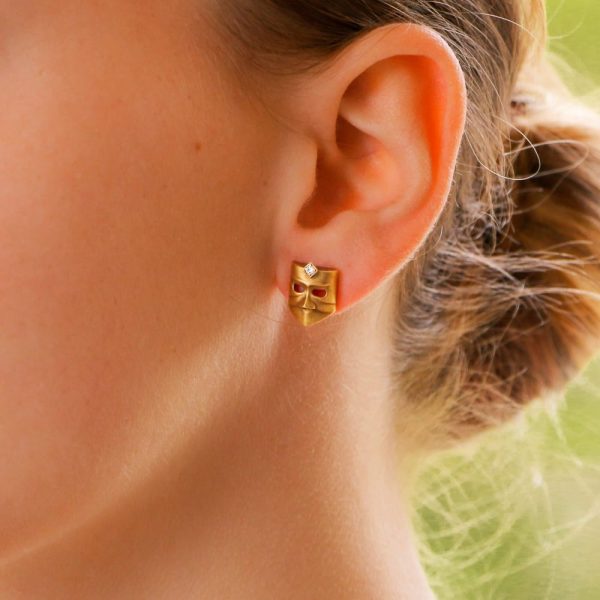 A pair of diamond masque stud earrings in gold. 