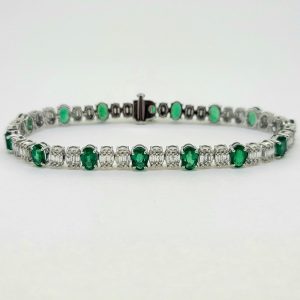 Oval Cut 6.72ct Emerald and Diamond Line Tennis Bracelet, fifteen oval-cut emeralds spaced with two oval-cut illusion set diamonds between each in 18ct white gold