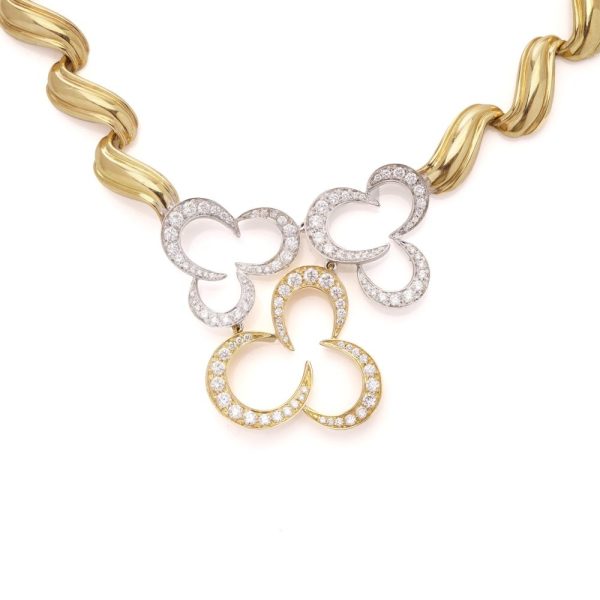 Gold necklace with three flower head pendants set with diamonds.