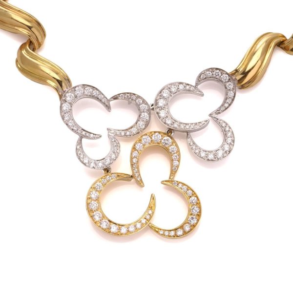 Gold necklace with three flower head pendants set with diamonds.