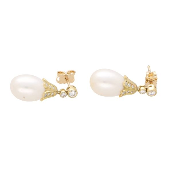 Pearl and diamond drop earrings in yellow gold.