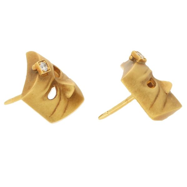 A pair of diamond masque stud earrings in gold. 