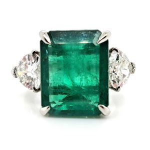 9ct Zambian Emerald and Heart Diamond Three Stone Ring with GIA Certificates, 9.08ct emerald-cut Zambian emerald flanked by GIA certified heart shaped diamonds in platinum