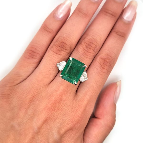 9ct Zambian Emerald and Heart Diamond Three Stone Ring with GIA Certificates, 9.08ct emerald-cut Zambian emerald flanked by GIA certified heart shaped diamonds in platinum