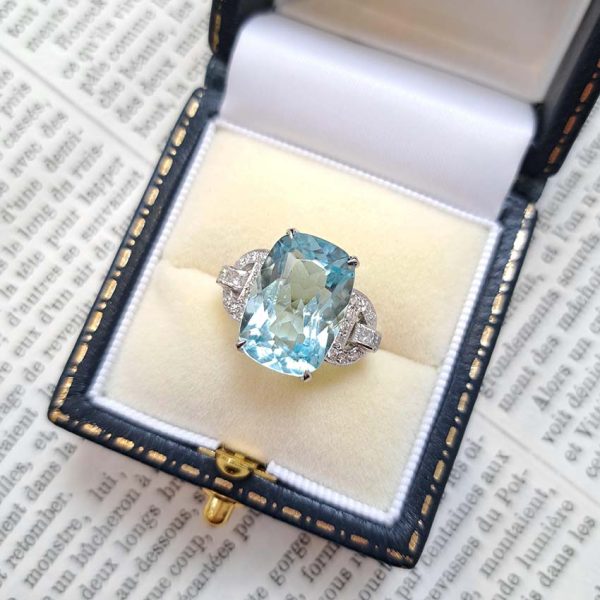 9.43ct Aquamarine and Diamond Dress Ring, large elongated cushion-cut aquamarine flanked by geometric buckle-design diamond-set shoulders in platinum