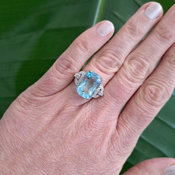 9.43ct Aquamarine and Diamond Dress Ring, large elongated cushion-cut aquamarine flanked by geometric buckle-design diamond-set shoulders in platinum