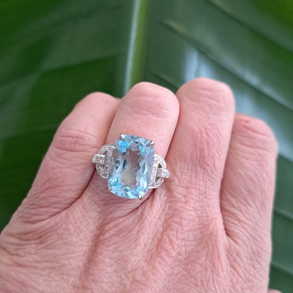 9.43ct Aquamarine and Diamond Dress Ring, large elongated cushion-cut aquamarine flanked by geometric buckle-design diamond-set shoulders in platinum