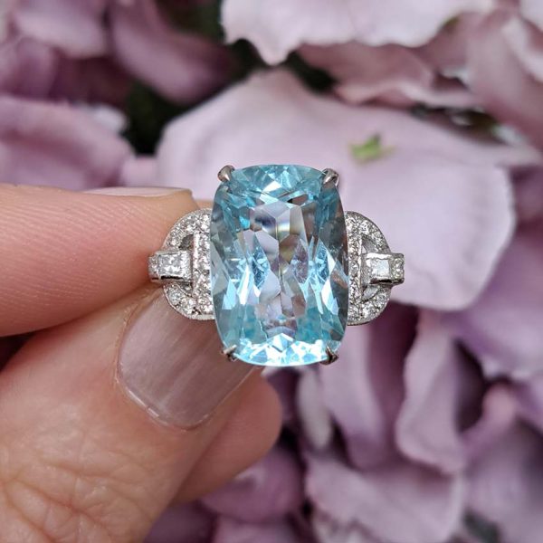 9.43ct Aquamarine and Diamond Dress Ring, large elongated cushion-cut aquamarine flanked by geometric buckle-design diamond-set shoulders in platinum